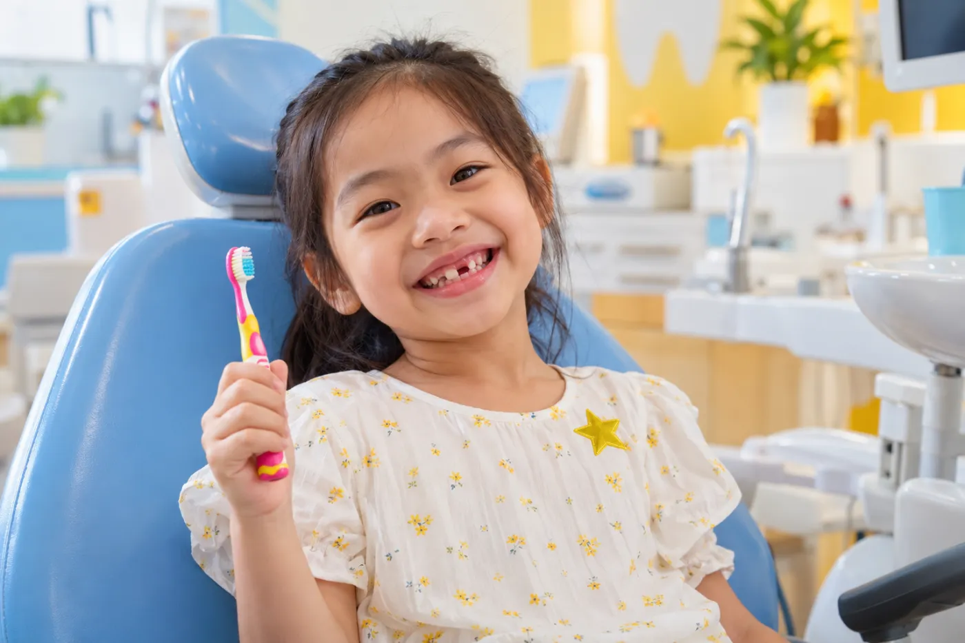Bé gái cười tươi cầm bàn chải sau khi khám răng